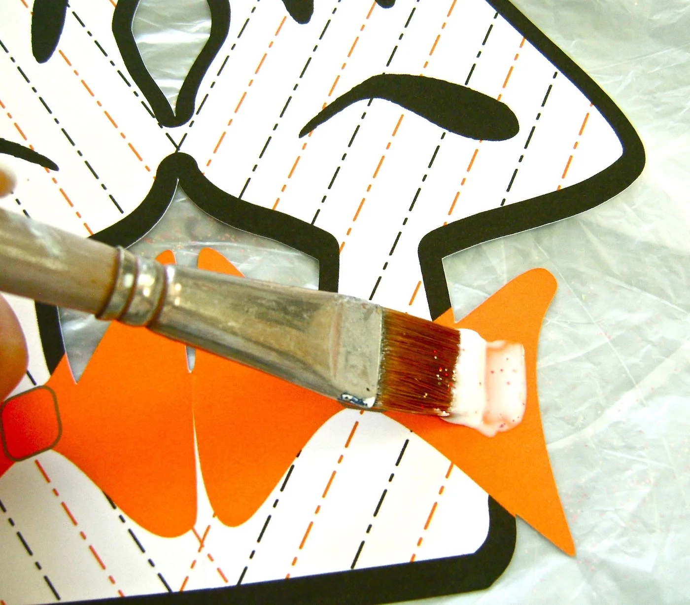 step 4 - Using a brush, apply Elmer's glue to the orange bow tie on all the ghosts then sprinkle with orange glitter. Shake off excess glitter and allow the glue to dry thoroughly.