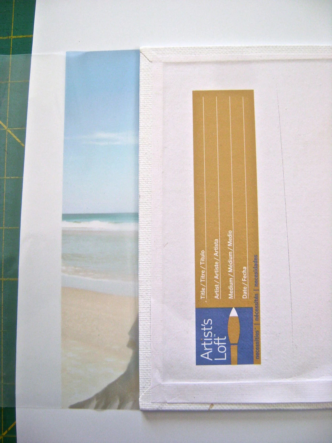 step 10 - Spray adhesive on the flat 5” x 7” canvas. Apply adhesive to the back edges too. Align the second printed film to the top of the flat canvas as you did with the first image. Wrap the sides around to the back and press to secure it. Cut away excess.