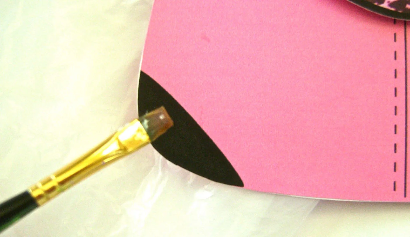 step 8 - Glue the purse handles with unprinted sides together. With a small brush apply Diamond glaze to one side of the handles. When dry, flip them over and glaze the other side. Paint glaze on the black bottom corners of the purse front. 