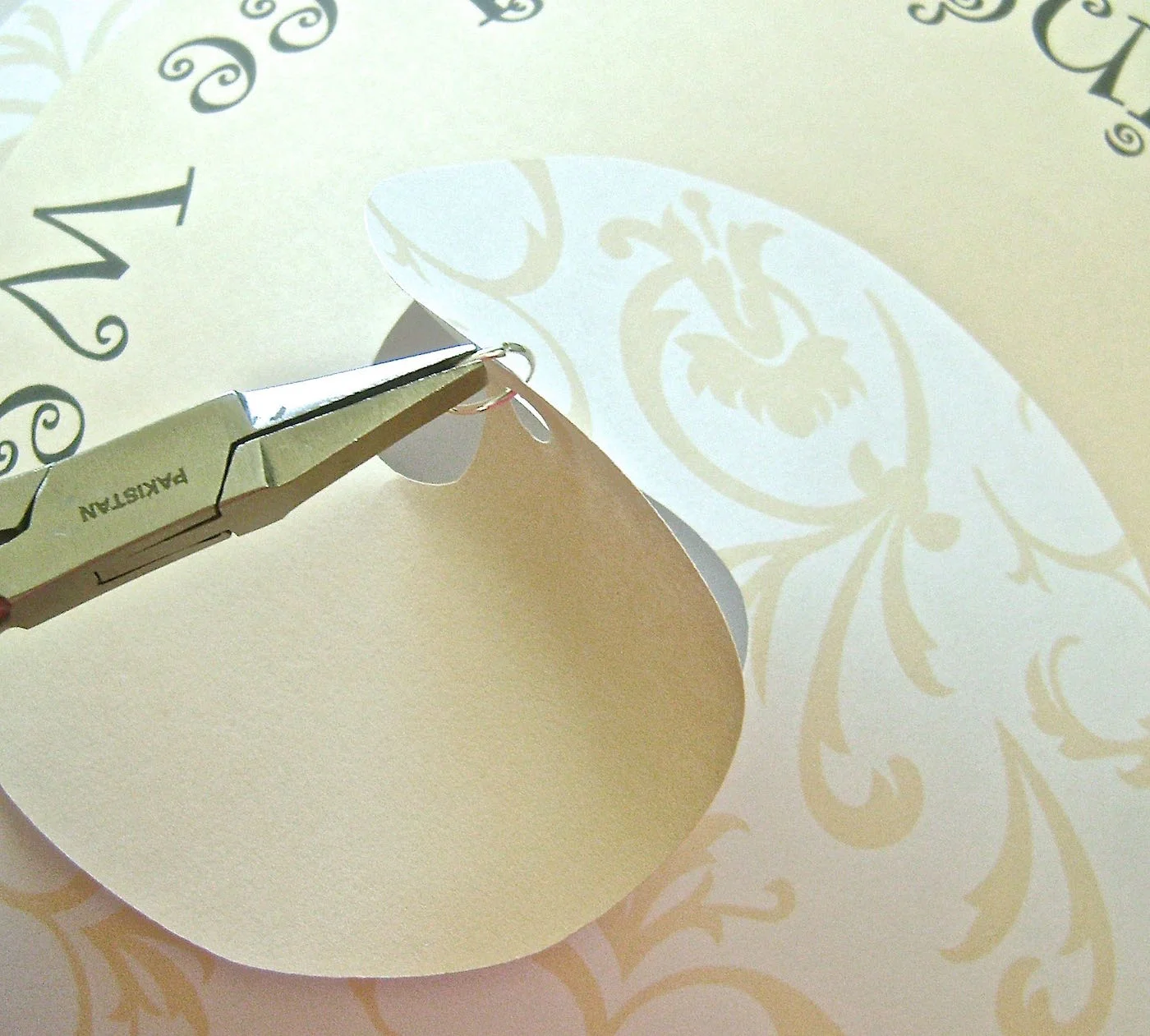 step 6 - Use jewelry pliers to insert a jump ring through the holes in both layers.