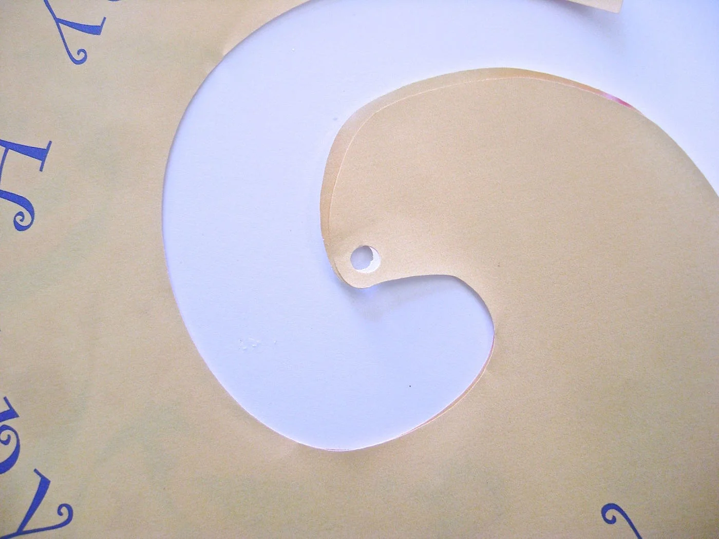 step 3 - Set the text layer on top of the floral layer. Match all edges. Use a paper punch to create a hole through both layers at once.