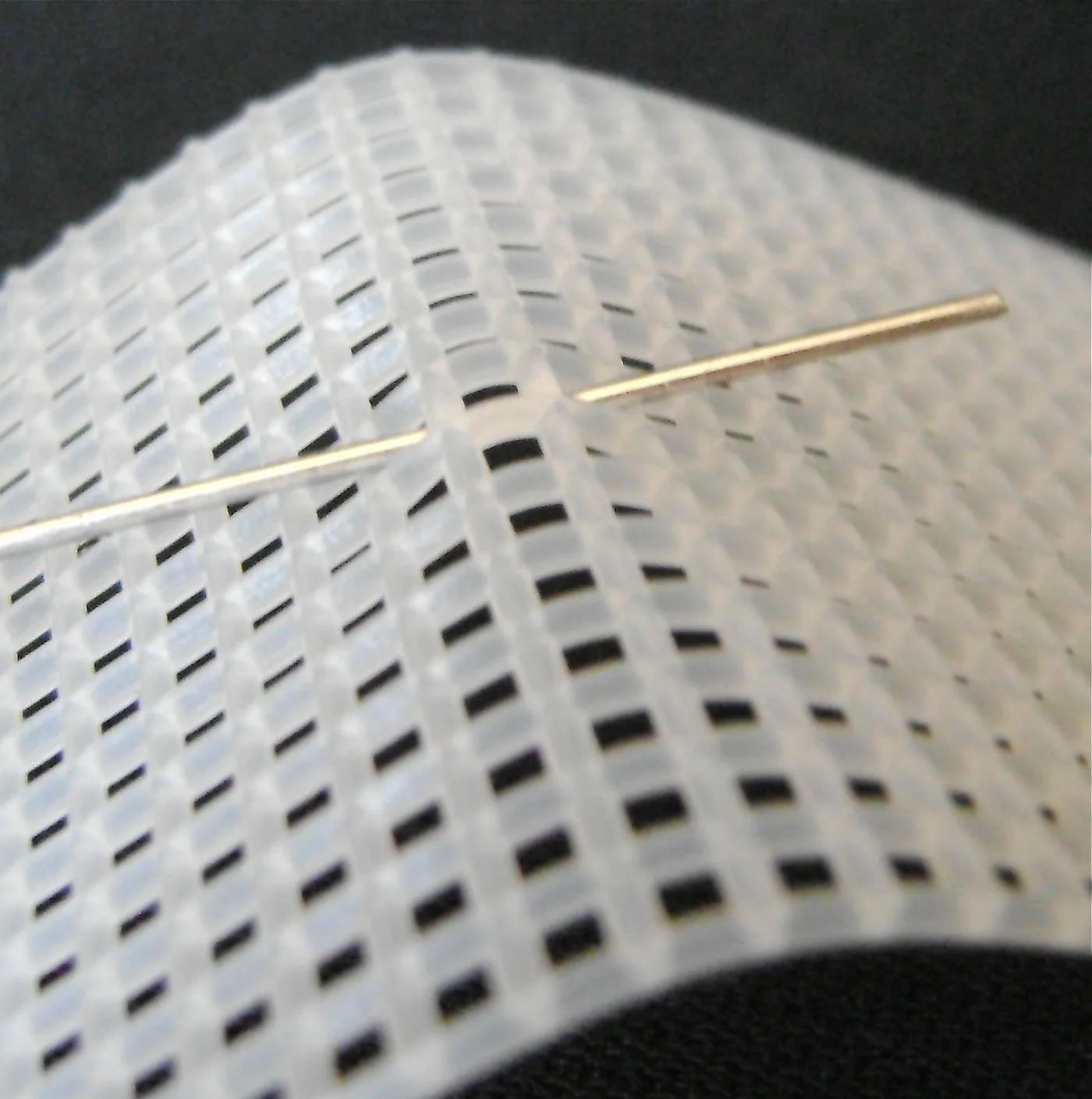 step 5 - Thread the remainder of that wire horizontally through the mesh, going into the hole left of center, skipping the center, then coming out the hole right of center. Curve the mesh slightly to help thread the wire without bending it.