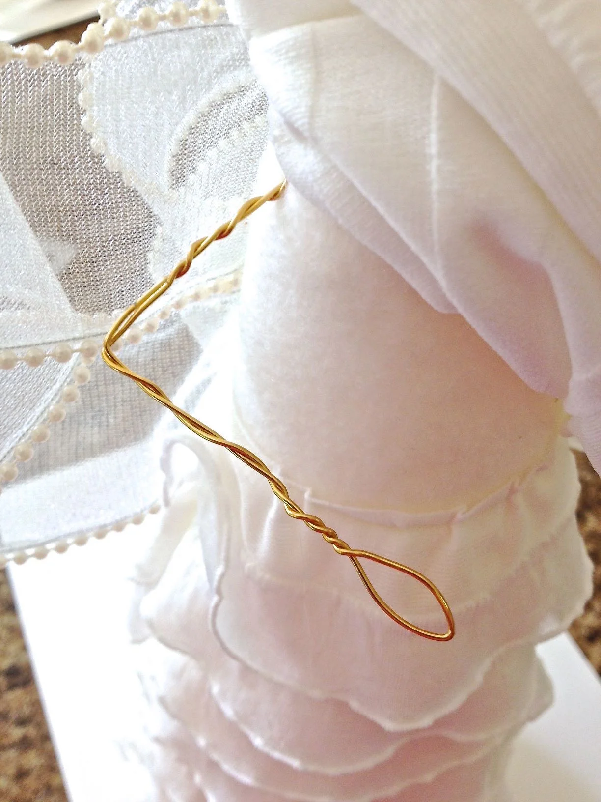 step 21 - Lift the ruffles out of the way before attaching the arms. Coat the ends of the arm wires with hot glue and poke them into the side of the angel body. You may need to first pierce the fabric with a sharp object to create a path for the wire. 