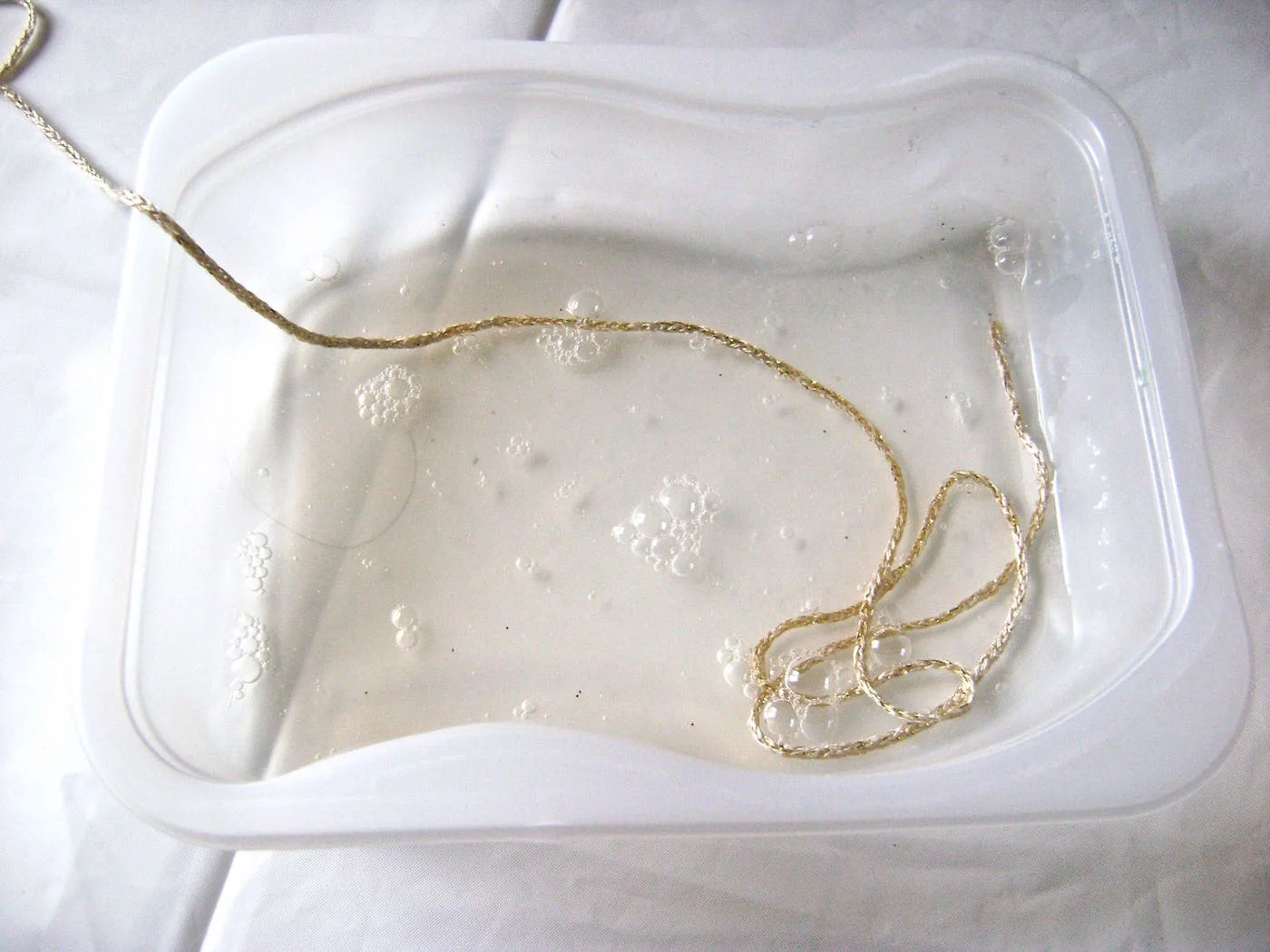 step 6 - Pour Fast Finish into a small, shallow, disposable container with enough of the decoupage to cover the yarn completely. The yarn needs to be saturated. Feed yarn into the liquid a yard or two at a time. Having too much yarn in the container can create knotting problems. 