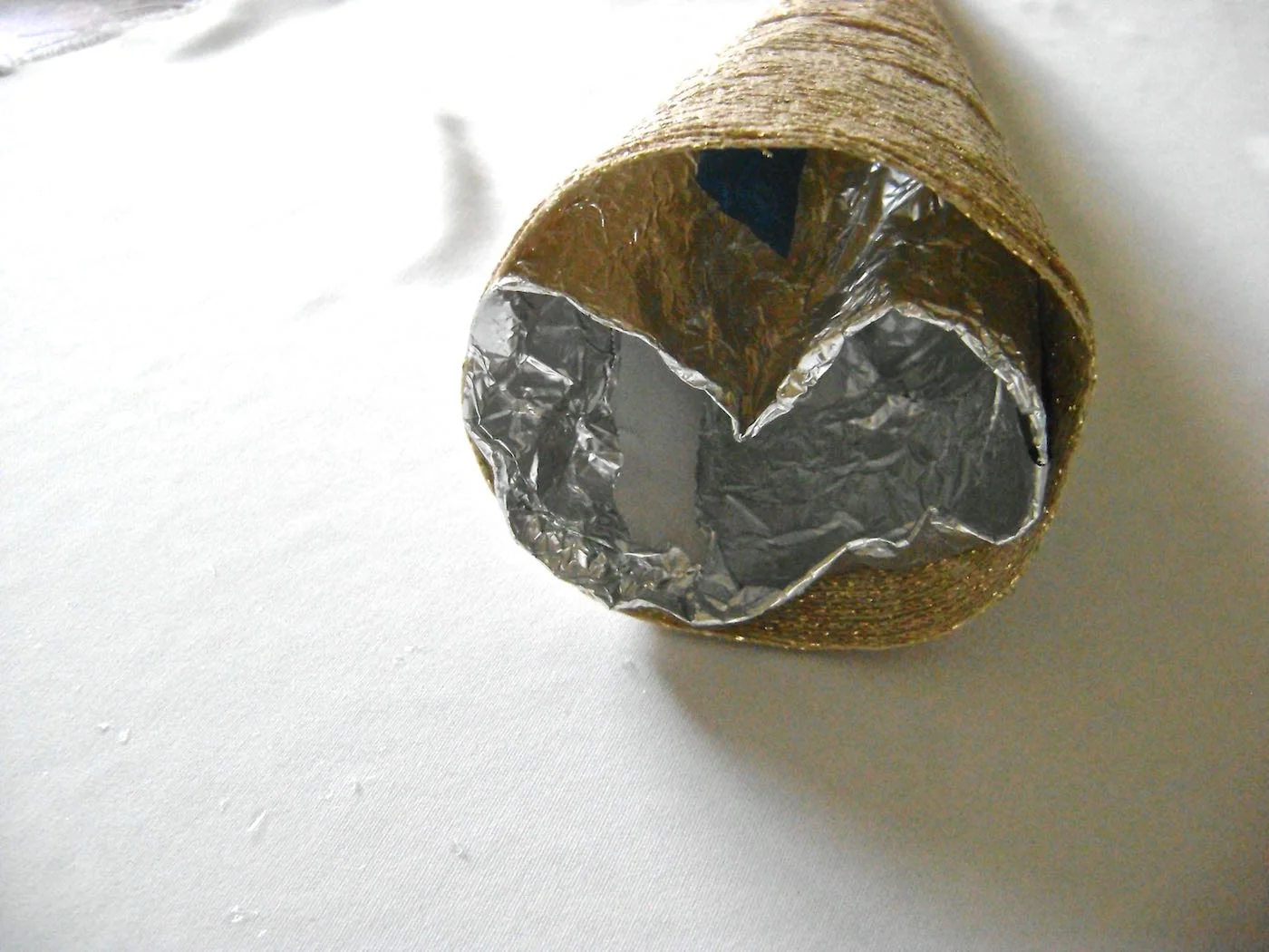 step 10 - Work your way up the cone, peeling the inner cone away from the yarn. Crush the foil inward and remove it from the yarn cone completely. Discard.