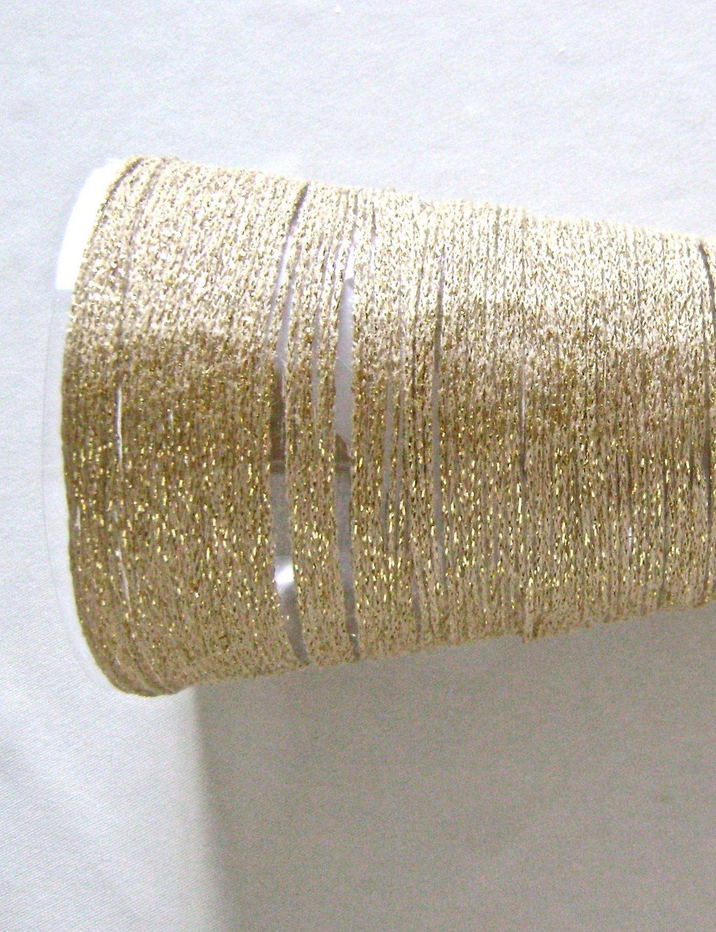 step 1 1 - Place the clear plastic cone into the yarn. Insert the light string, bringing the end without the battery pack up to the very top of the cone. Slip the wire end out the top and bend it over the tip of the cone to hold the light string in place. Arrange the lights inside by shaping the wire they’re attached to distribute them evenly. Set the cone on a pedestal candle holder.