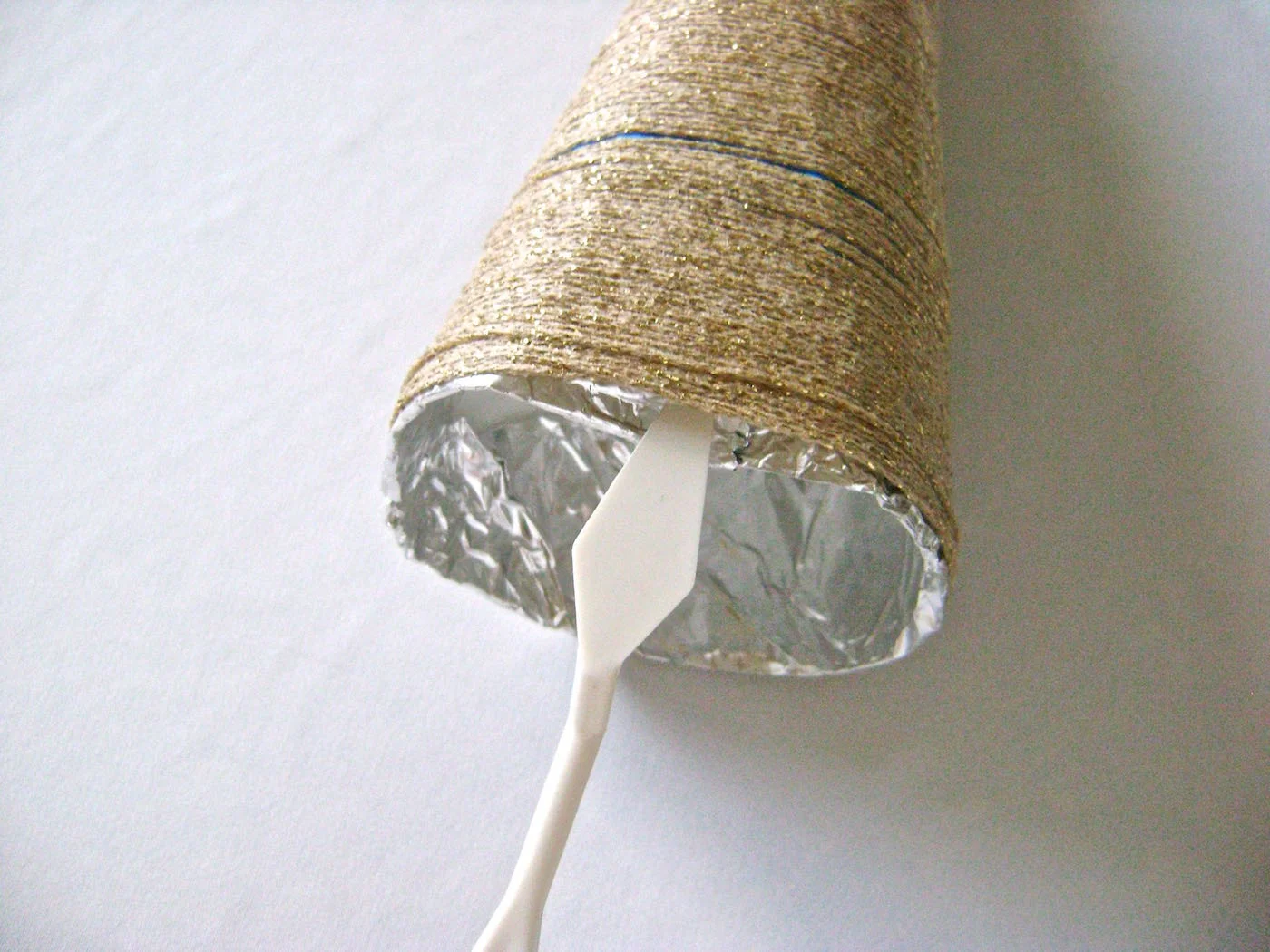 step 9 - Insert a plastic knife between the aluminum cone and the yarn and slip it around the bottom to separate the two layers.