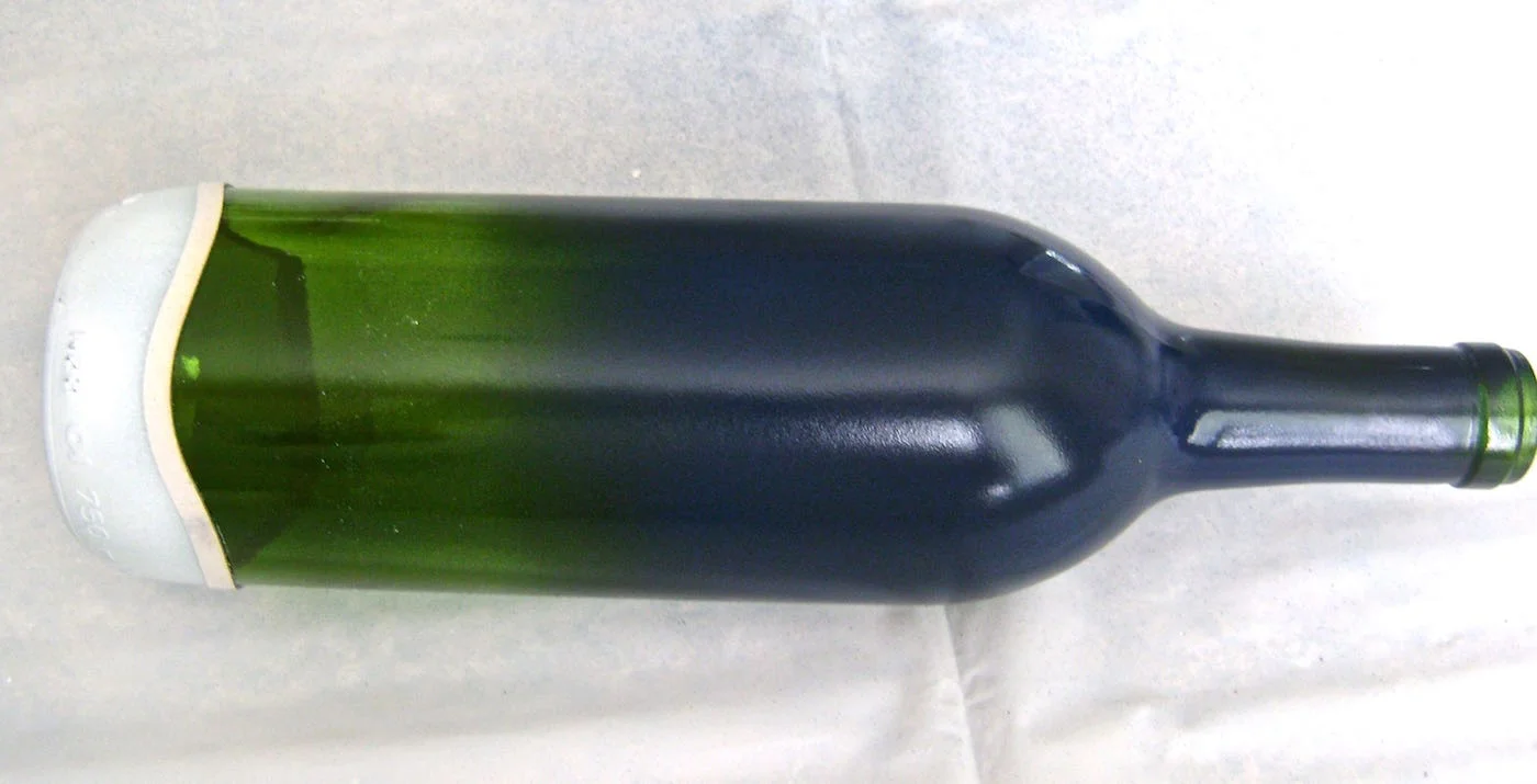step 4 - Mix a little black with the blue paint to create a midnight blue effect. Airbrush the top two-thirds of the bottle with a light coat of blue paint. If the paint is applied too heavily, it will lift off later when the stencil is removed. Leave a small portion of the bottle’s green color unpainted.