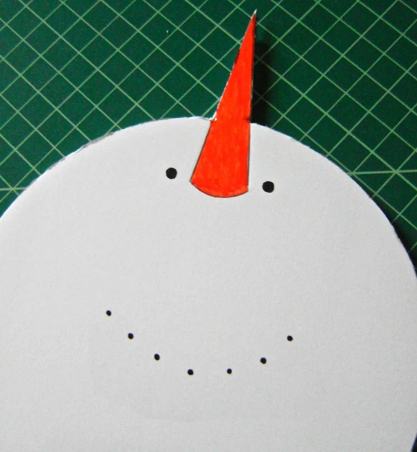 step 3 - Cut out the completed snowman shape with the craft knife. Smooth the edges of the foam board with sandpaper. Use orange paint to color the nose. Outline the color with a black marker. Use the marker to create the eyes, mouth, and buttons down the center of the middle circle.