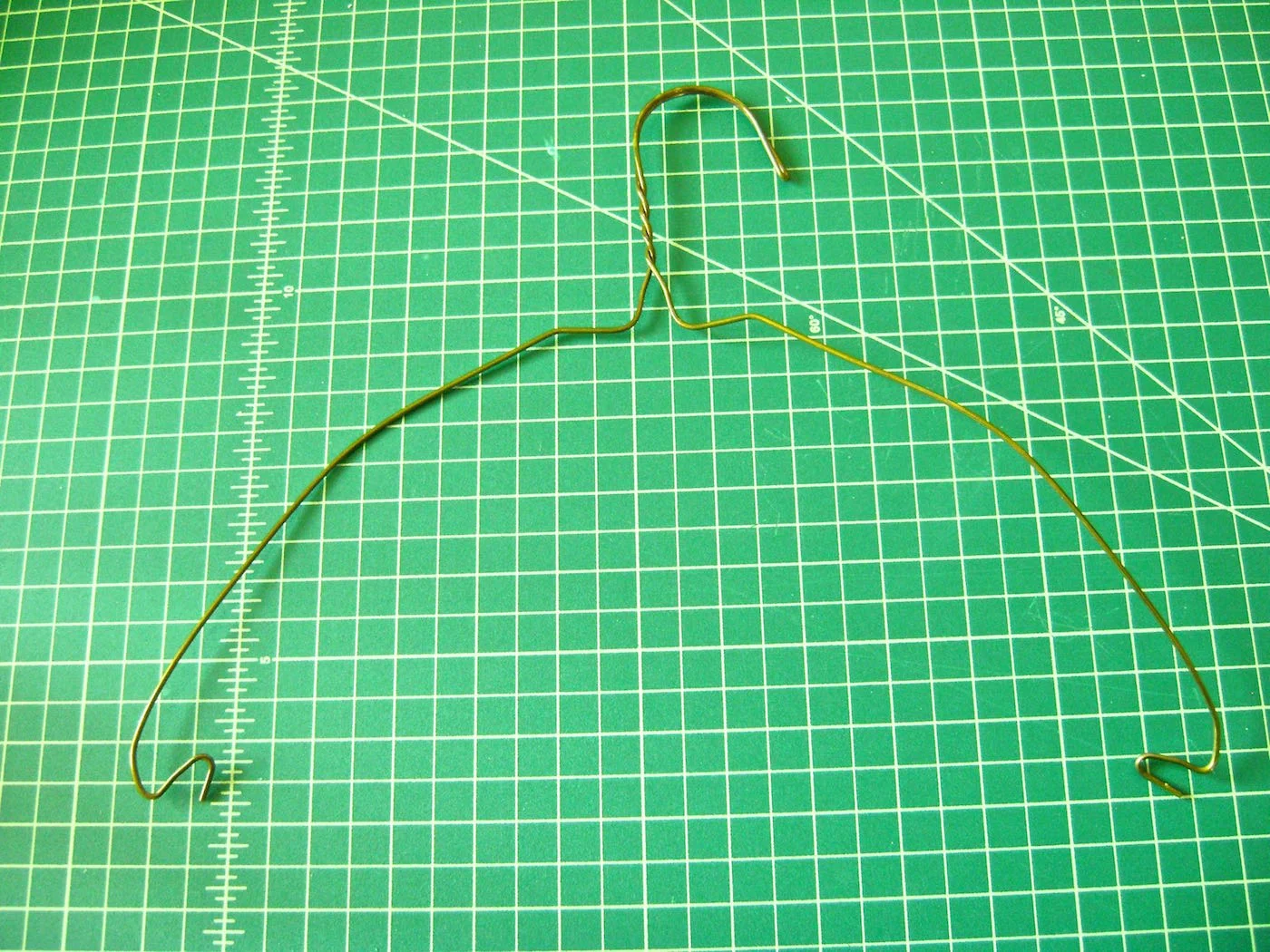 step 6 - The Mesh Hanger Twist the white tube between the wire sides of the hanger to remove it. Use pliers to straighten the bent ends and bend both wires over your thigh into an outward arched shape.