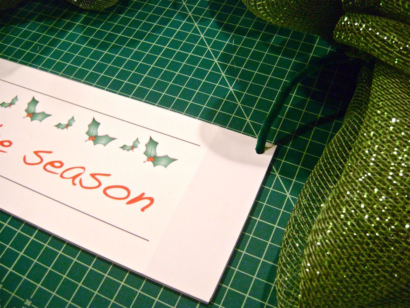 step 10 - The Plaque Greeting Using foam board scraps, cut out a plaque for the message measuring 14" x 5". Print out the free message template and center it on the plaque. Adhere the page with spray adhesive. Poke a hole into the upper corners of the plaque and insert the pipe cleaner ends. Twist it with the matching end to hold the plaque.