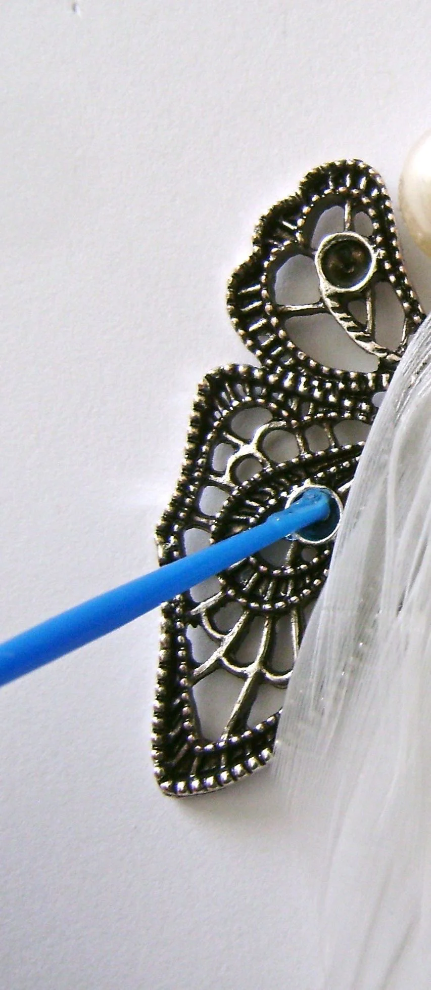 step 6 - Dab glue into the hollowed out spot on each wing and add a seed pearl. 