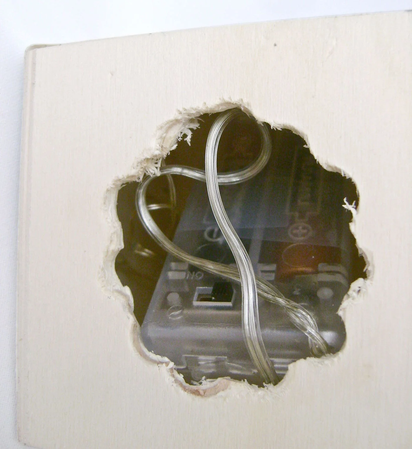 step 3 - With a large drill bit, drill holes close together in a circle on the bottom of the cube. Use pliers to break the separation between the holes and create an opening large enough to insert the battery pack at angle.
