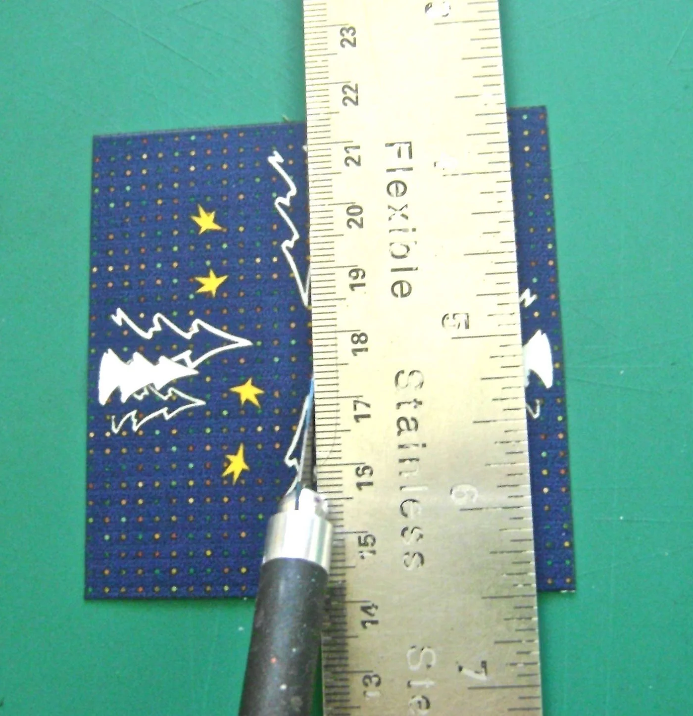step 6 - Spray the cube top with adhesive. With a craft knife or scissors, make a slit across the top film piece from the center to one side edge. Make a small cross slit at the center. Slip the film around the wire, matching all the outer corners and press in place.
