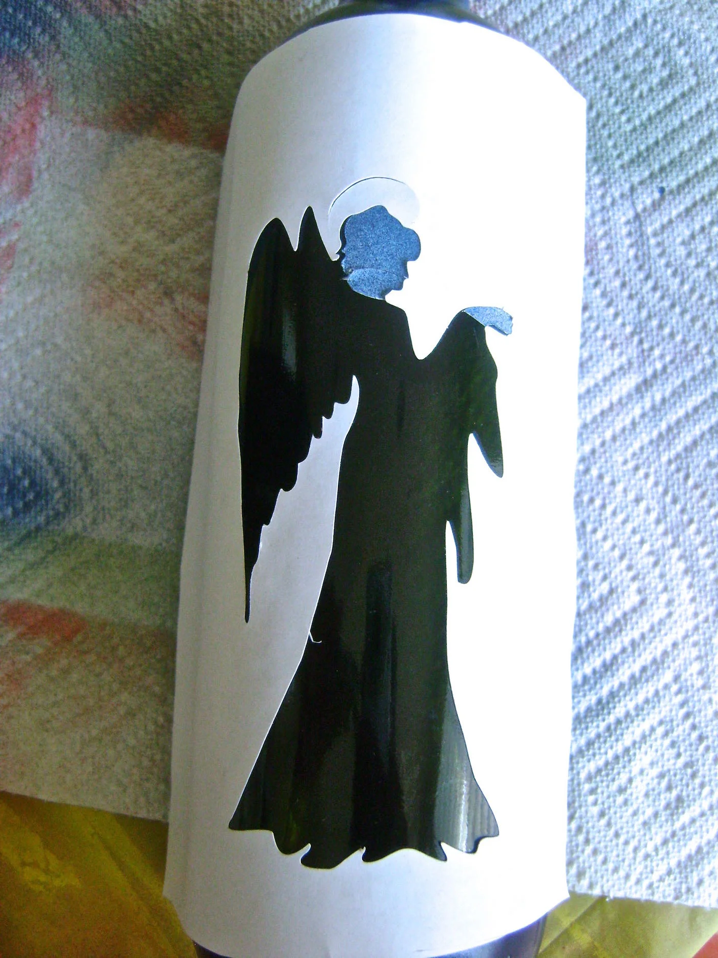 step 6 - Peel off the positive image cutting the stencil to leave the head and hand on the bottle. Stick the negative stencil in position on the bottle.