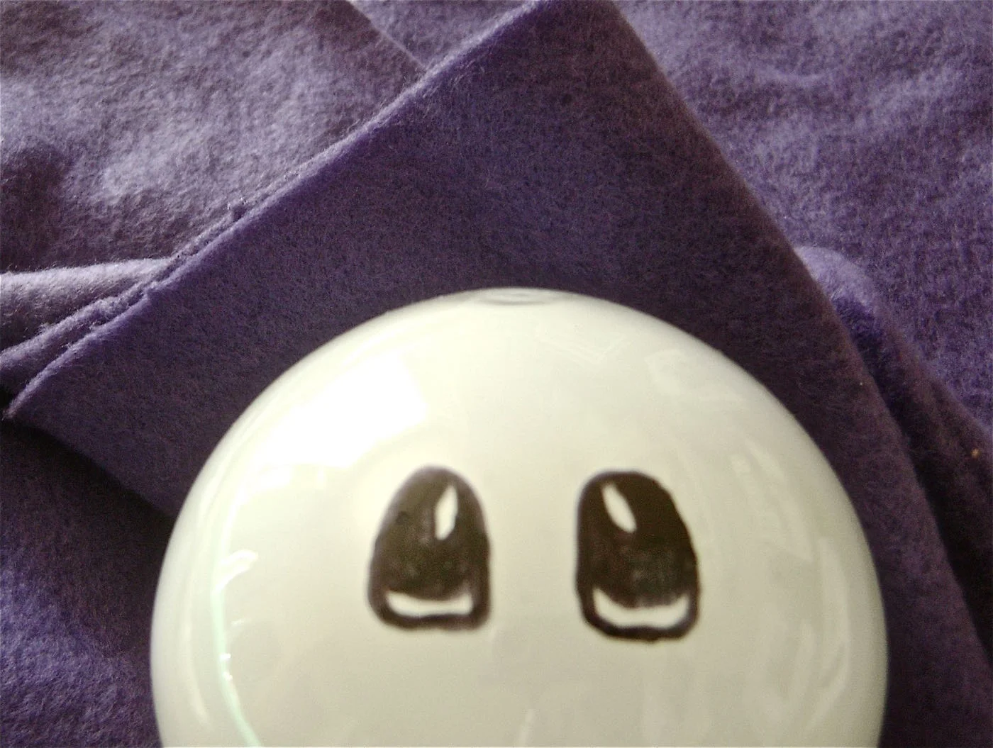step 1 - To keep the bulb from rolling around, cradle it in soft thick fabric, like fleece. Use a thin, black Sharpie to draw the eyes. Start with the outline of the eyes, then fill in with thicker marker. Don’t worry about making mistakes. Any errors can be wiped away with a Q-tip dipped in rubbing alcohol.