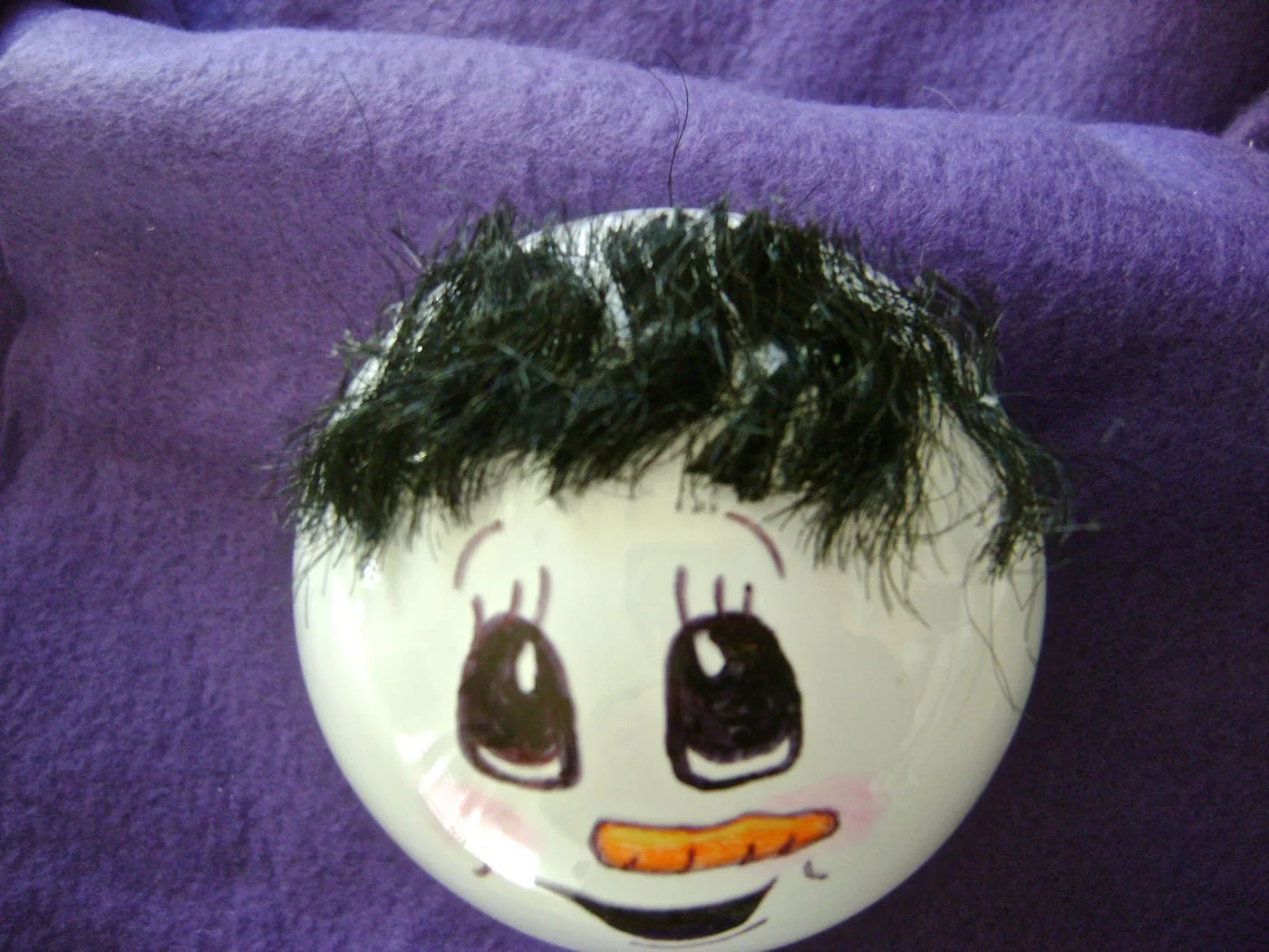 step 6 - Apply hot glue in a line across the top of the head then drape doll hair across the glue line. Don’t worry about the hair length. Trim the hair once it is in place and secured to the glue.