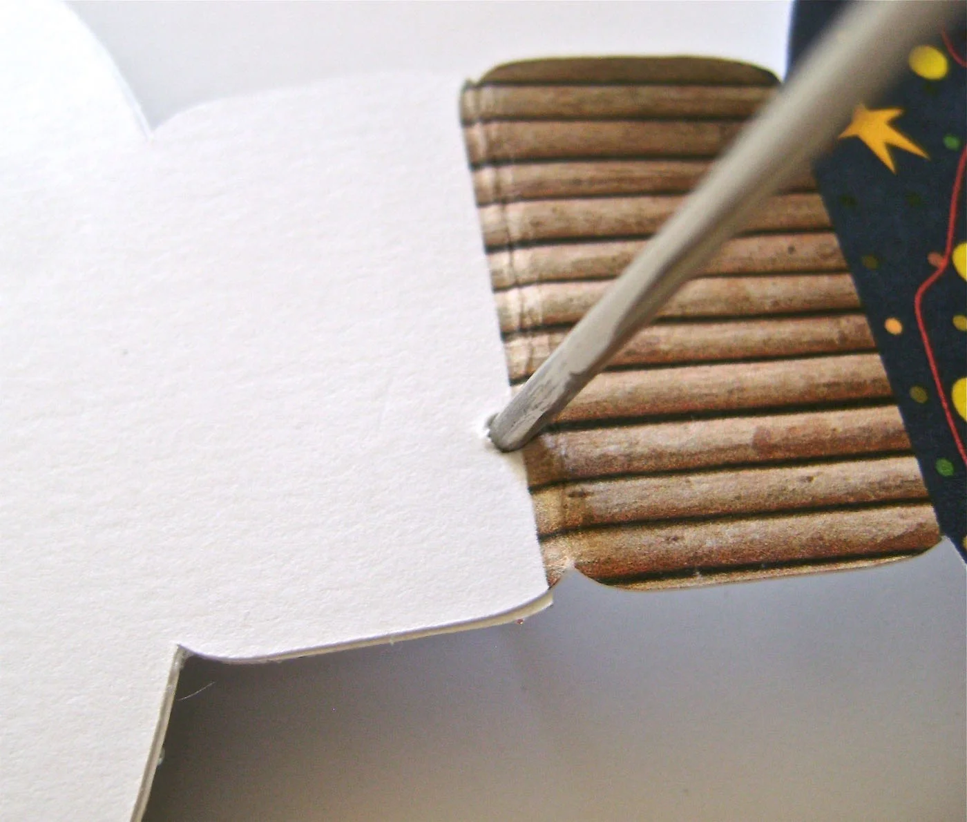 step 6 - With a thick darning needle, poke two holes at the top of the back flap close to the printed edge.
