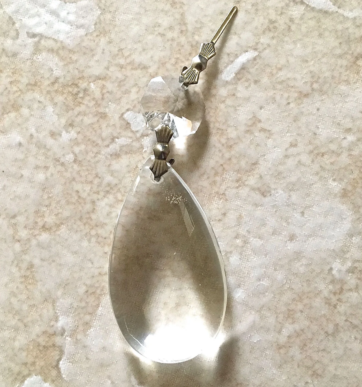 step 1 - Carefully bend the metal prong to remove the round crystal from the teardrop shape. Set it aside to replace it later.