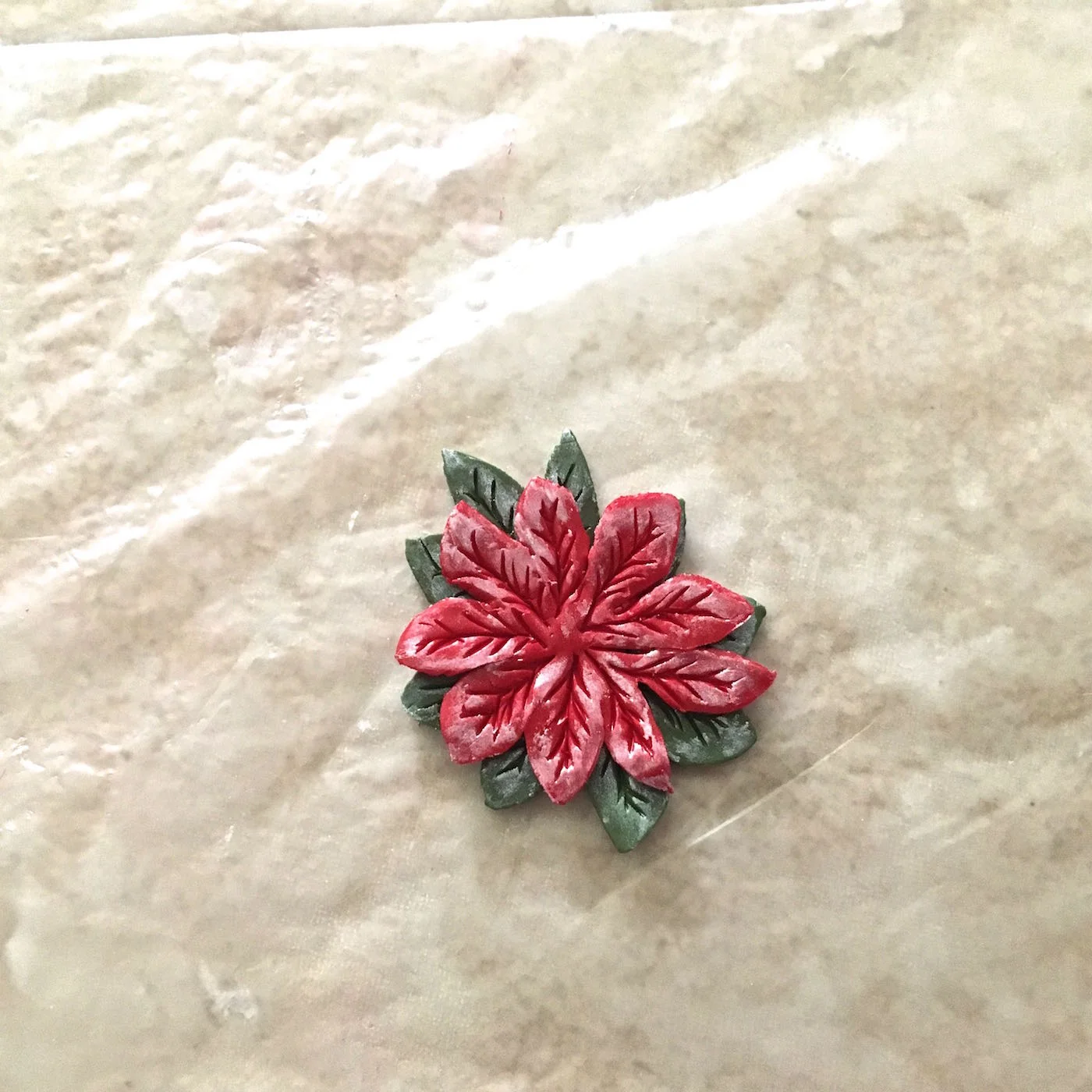 step 6 - Stack the largest red clay piece onto one of the green ones. Don’t match the shapes. Rotate the top piece so that the points of the red leaves fall between the green leaves.