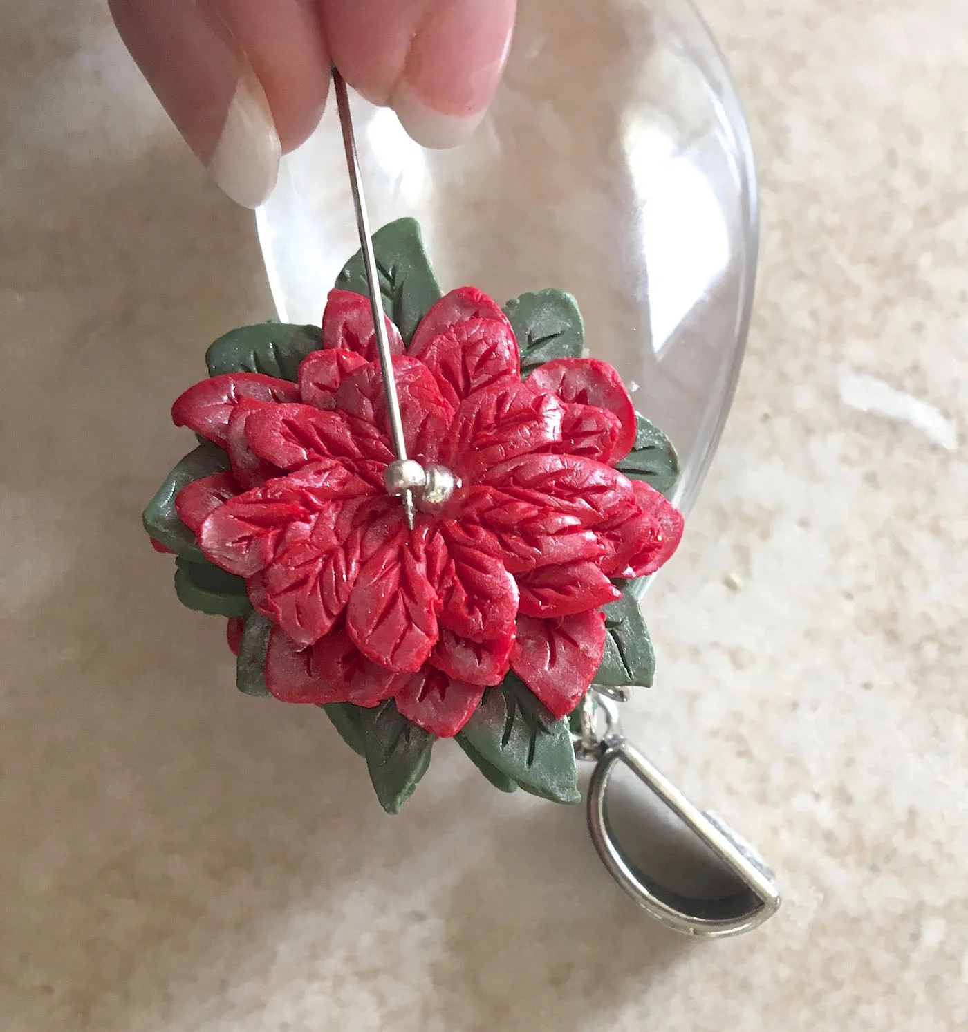 step 13 - When the clay has cooled, drop a bit of E-6000 into the center of each poinsettia and attach silver seed beads. Positioning the bead on a straight pin and sliding it into position will prevent the bead hole from landing face up.
