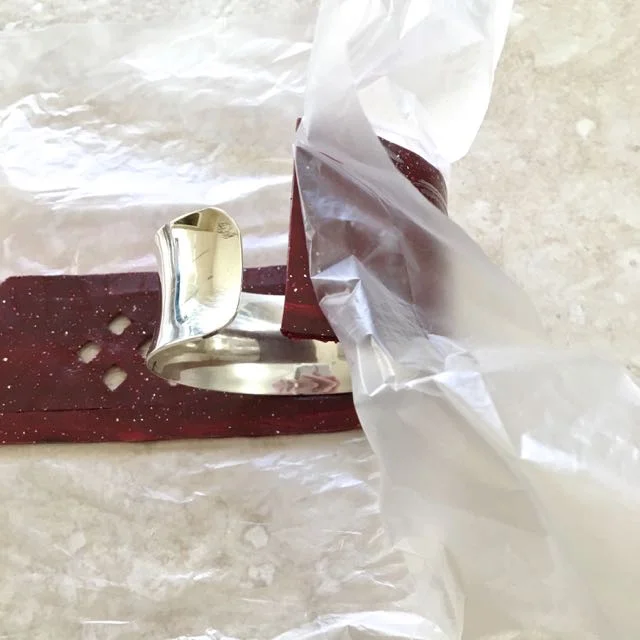 step 15 - Use the film to wrap the clay onto the cuff, first one side then the other. Press lightly to the metal then remove the film. Adjust the clay if necessary.