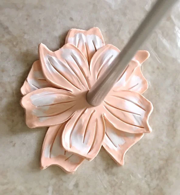 step 9 - Use the pointy end of the Etch N’ Pearl tool to create curved lines on each petal. Place the smaller layer over the larger one. Don’t match them up perfectly. Position the top layer petals over the spaces between the bottom layer petals. Press the concave end of the Etch N’ Pearl tool into the center to join the two petal layers.