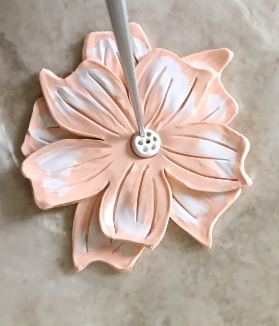 step 10 - Cut out a perfect white clay circle with the Etch N’ Pearl tool. Place the circle in the center of the flower. Use the tool’s pointy end to create decorative holes in the clay.