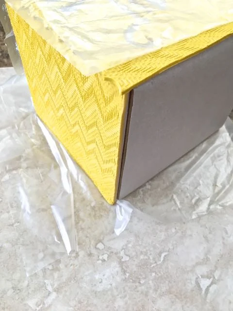 step 12 - Use a very small dab of Liquid Polymer to temporarily hold the top panel to the form while you work. Lay the form on its side. Attach the first side panel matching the fluted edge to the roof panel. Press them together to make contact with the Liquid Polymer. Cover the first panel with deli film.