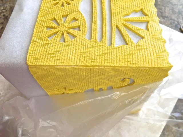 step 13 - Be sure your surface is also covered with deli film. Roll the cube over and attach the second panel to the roof at the top fluted edge. Bring the side edges of the first and second panels together. Pinch the seam to seal the pieces.
