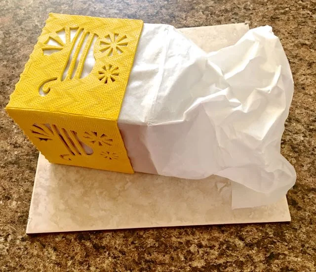step 8 - Cover your cube form with parchment paper. Cut it longer than the form. The extra length will allow you to tuck it into the bottom of your form and keep the paper in place as you work. (This photo was taken after baking and right before removing the form but demonstrates the length of the parchment paper compared to the form.)