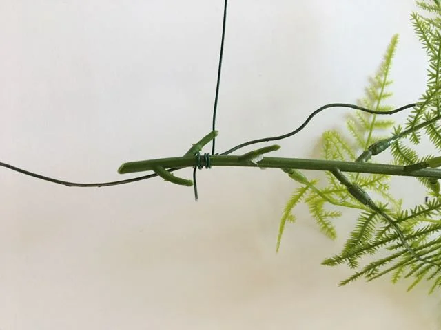step 23 - Using 24-gauge wire, wrap stems of greenery to the hanger wire, concealing it completely.