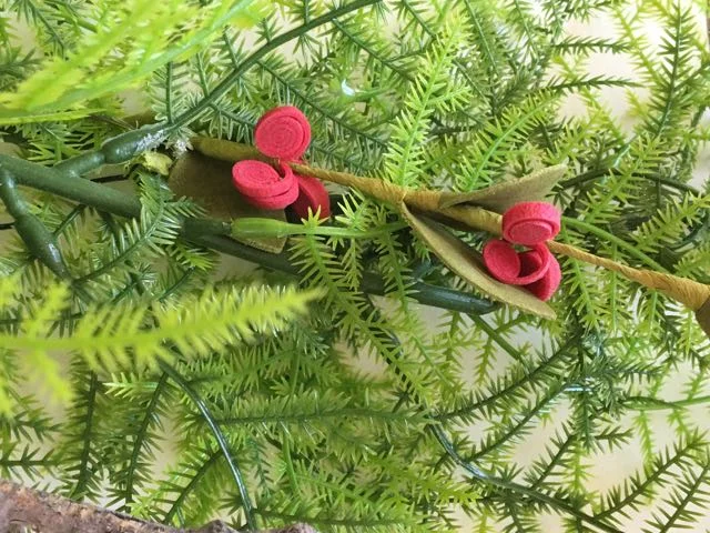 step 24 - Hot glue tiny red floral stems to the greens.