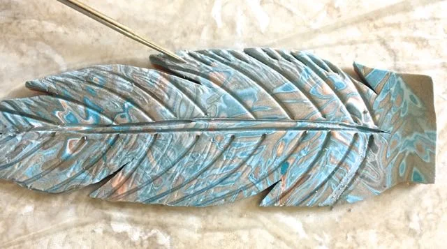 step 15 - Continue creating lines on both sides of the feather. Use a pointy sculpting tool to make short indentations on the feather edges.