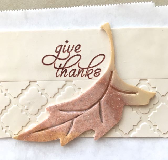 Step 13 - Press the leaf to the right of the lettering on the clay band.
