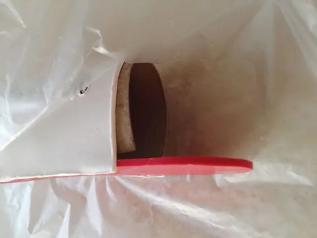 Step 10 - Position the cardboard tube then wrap the clay body over it, pressing the clay edges to the Liquid Polymer. Work around the curve of the red clay pressing it to seal the back wall of the mailbox to the body.