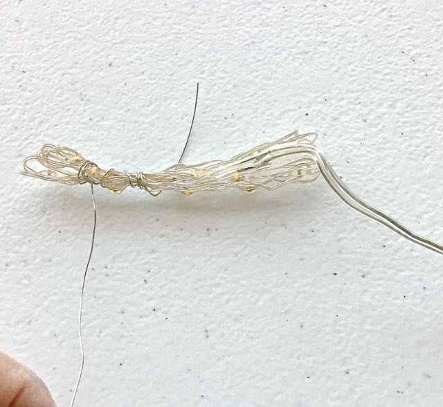 step 10 - Place batteries in the battery pack. Loop the light wire back and forth around your fingers so it measures no more than 3.50" long. Wrap 26 gauge wire three or four times around the left and right looped ends. Leave 4" long tails on the wires and snip away the rest.