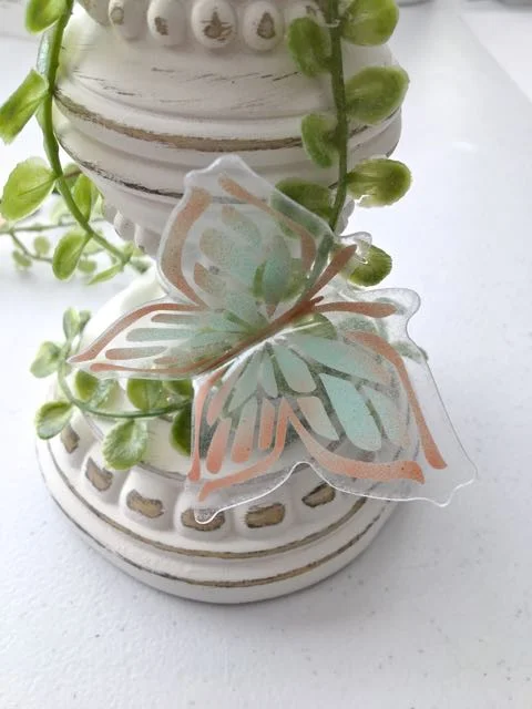 step 14 - Hot glue the butterflies to the greens. Distribute them around the candle pillar on all sides, alternating the sizes and colors.
