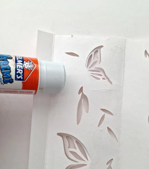 step 8 - Turn the sheet over. Apply glue to each panel. Avoid the cut out areas and butterfly wings. 