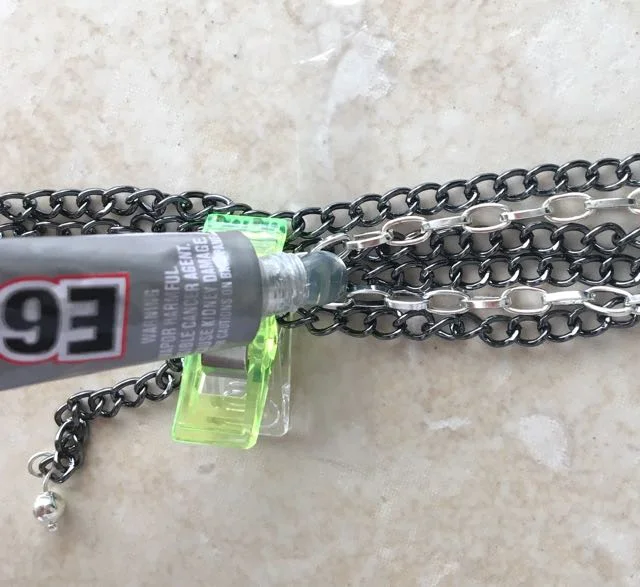 step 6 - Apply a glob of E6000 to the chains and the plastic just above the clip. Use a toothpick to move the glue around making sure the chains make contact with the adhesive and the plastic. Allow the glue to set.