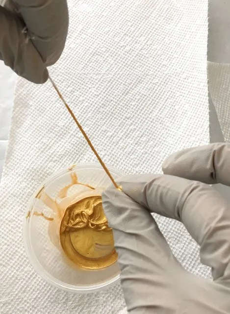 step 4 - Starting at the knot end, run the entire floss between your gloved index finger and thumb. Wipe excess paint from your fingers on a paper towel and repeat once more.