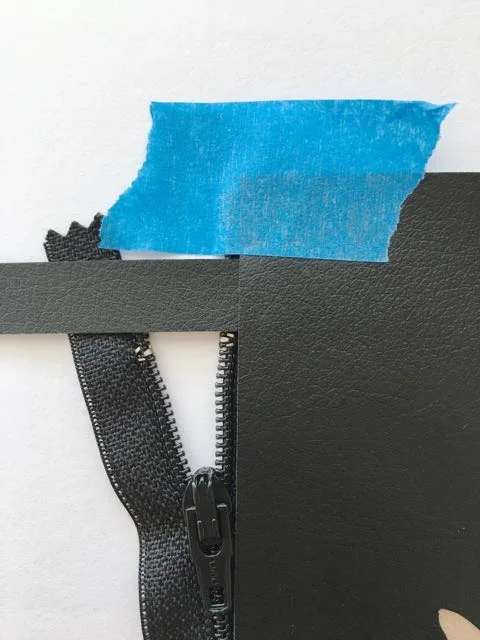 step 9 - Cut the thin black strip into two 1" wide pieces which will act as zipper stops. Place one piece across the top of the zipper, between the two panels, .50" from the panel's side edge. Do the same at the bottom of the zipper. Use clips or tape to hold the pieces together.