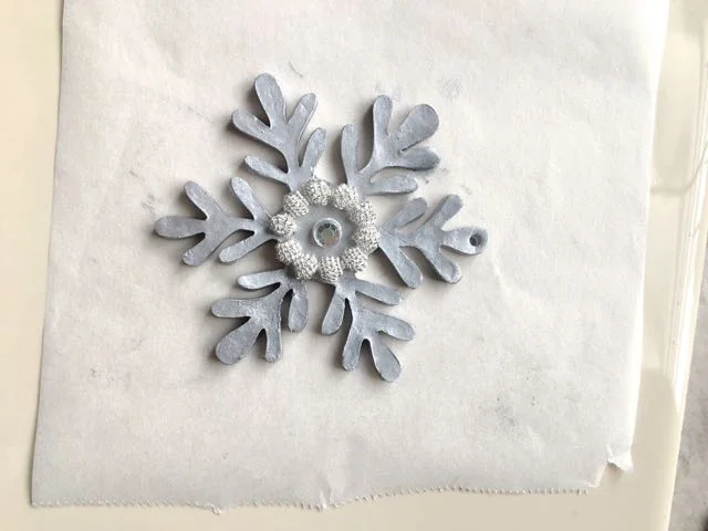 step 19 - Surround the rhinestone with textured silver beads. Press them into the clay. Fill the space between the beads and the rhinestone with smaller rhinestones.