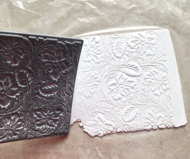 step 4 - Press the stamp to the clay. Syndee Holt recommends putting the tile on a hard floor and standing on the back of the stamp for the best impression. It works great!