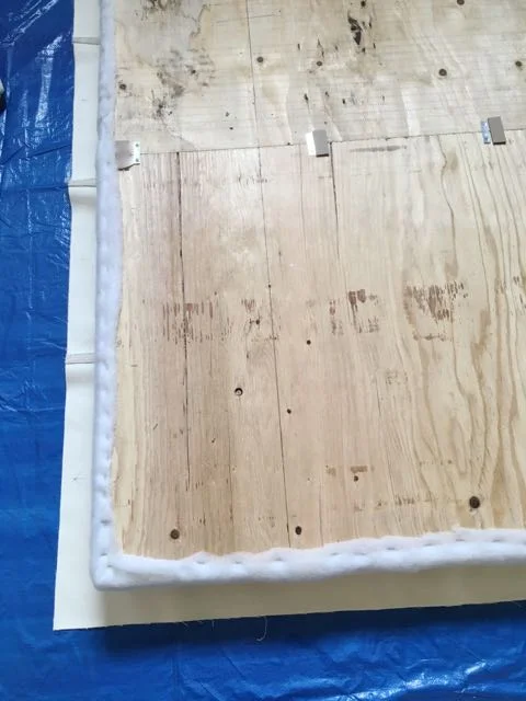 step 16 - Assembly - Lay the fabric wrong side up in the workspace and center the cushioned side of the plywood face down.