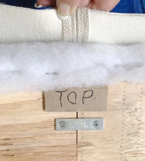 step 17 - Starting at the center top, pull the fabric to the back of the plywood, over the batting and apply a few staples.