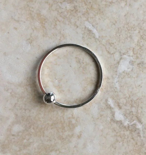 step 8 - If your metal ring is not open, use jewelry cutters to slice it open. Open the ring the same way you would a jump ring by pushing back on one side while holding the other side stationary. Slip a 6mm silver ball bead on the ring. Bring the two sides of the ring together again so the edges match.