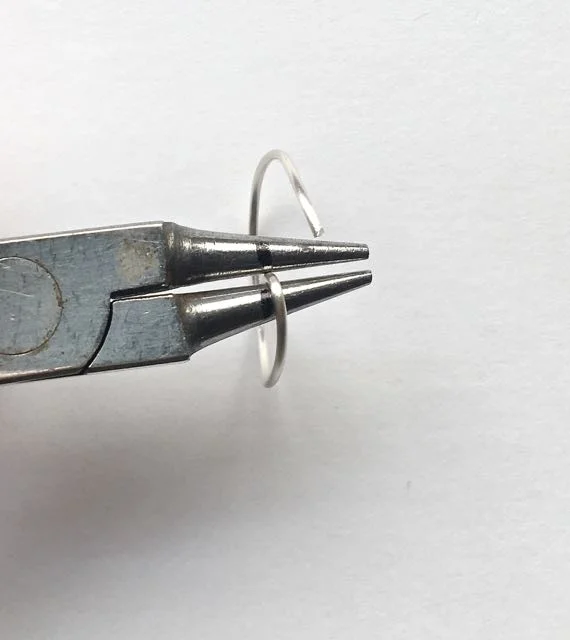 step 7 - Grasp the wire at that mark and curl the end. Repeat with the other cut wire end. You will need three of these shapes.