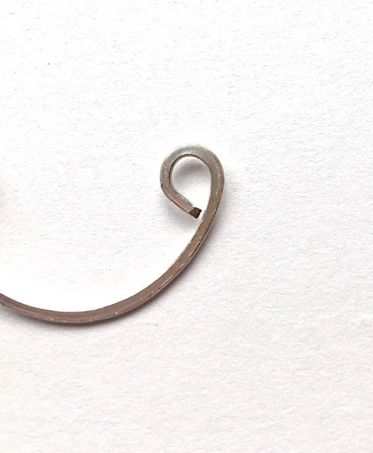 step 8 - Flatten the three curved wire shapes with the chasing hammer. The curls may tend to open slightly. After they are flattened, close them with flat nose pliers.