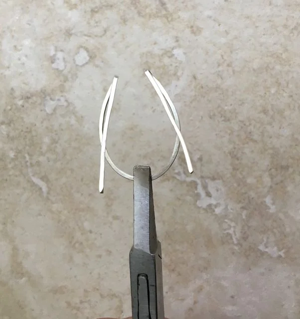 step 5 - Hold the wire with flat nose pliers over the center mark and pinch the folds closer together. There should be approximately 3/8” in between them.